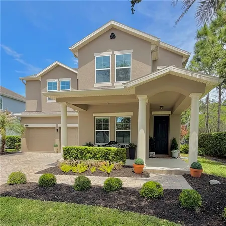 a front view of a house with garden and trees