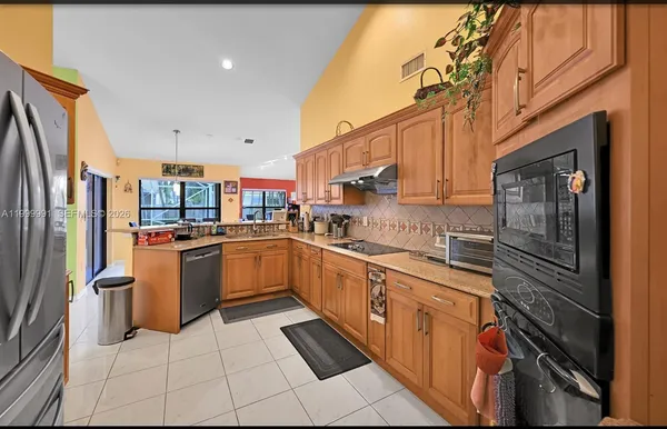 a kitchen with stainless steel appliances granite countertop a refrigerator and a stove top oven