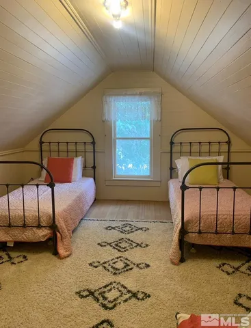 a bedroom with a bed a dresser next to a window