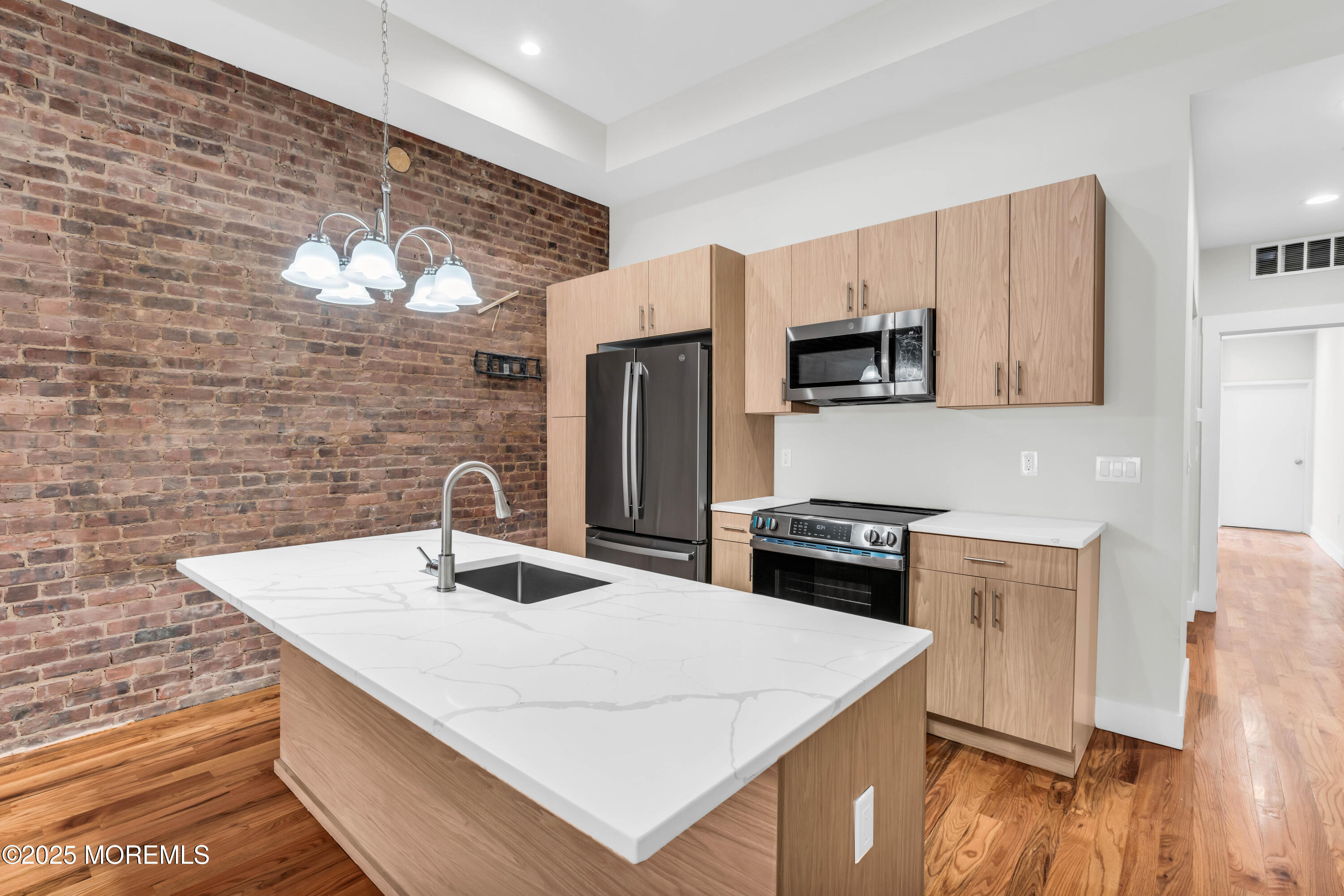 7 Broad Street, Unit 1 Red Bank, NJ 07701 - Photo 7 of 28 a kitchen with stainless steel appliances a stove a sink a microwave a refrigerator white cabinets and wooden floor