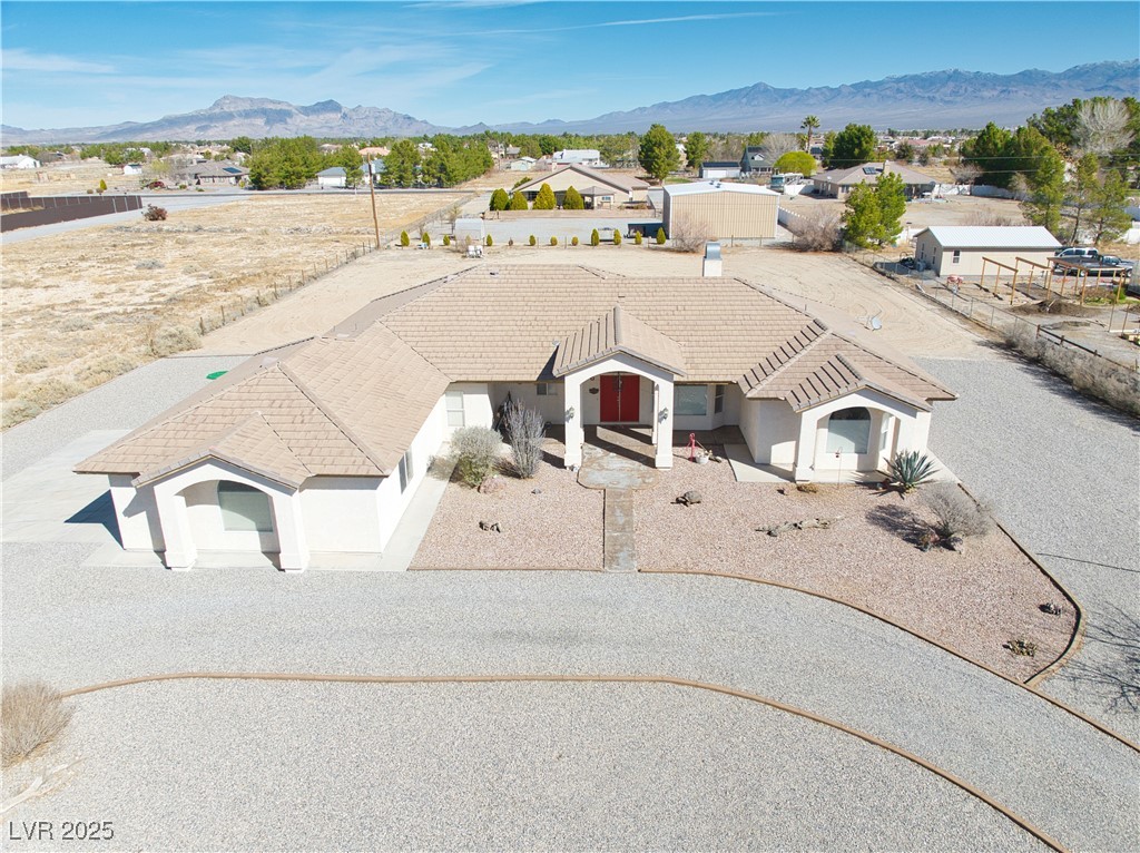 660 Indian Road Pahrump, NV 89048 - Photo 2 of 54 Front features multiple decorative mediterranian-style arches, concrete-tile roof, decorative concrete curbing, & over 385 tons of 3/4 inch multi-color stone. Note: 3-car garage on west-side of home (left-side of image).