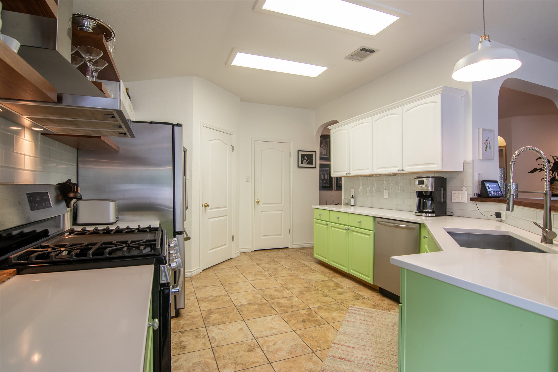 8901 Copano Drive Austin, TX 78749 - Photo 12 of 29 The renovated kitchen showcases vibrant accents, stainless steel appliances, a gas range with vent hood, and modern open shelving for a stylish, updated feel.