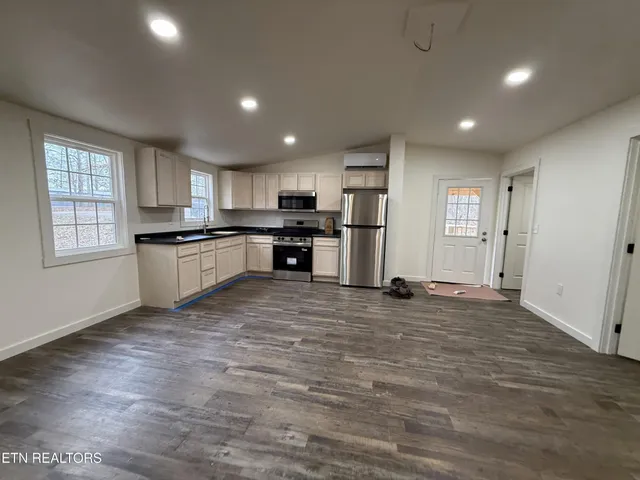 a kitchen with a refrigerator a stove top oven a sink and dishwasher with wooden floor