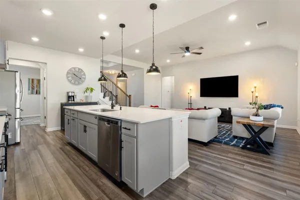 a large kitchen with a large counter space a sink appliances and wooden floor
