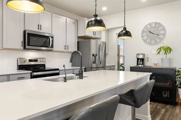 a kitchen with stainless steel appliances a table chairs stove and microwave