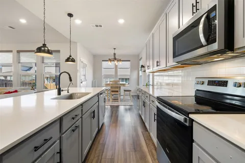 a kitchen with stainless steel appliances granite countertop a sink a stove and a wooden floors