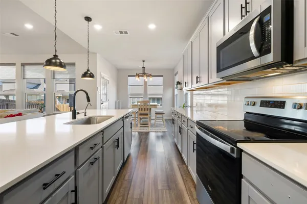 a kitchen with stainless steel appliances granite countertop a sink a stove and a wooden floors