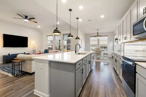 a kitchen with stainless steel appliances granite countertop a sink a stove and a wooden floors