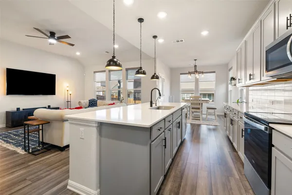 a kitchen with stainless steel appliances granite countertop a sink a stove and a wooden floors