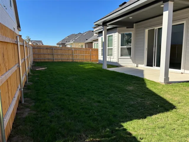 a view of a backyard with plants and large trees
