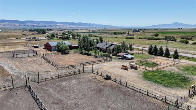 1634 West Arimo Road Arimo, ID 83214 - Photo 81 of 89 Expansive rural property featuring multiple fenced paddocks, a circular pen, and a large red barn with a silver roof