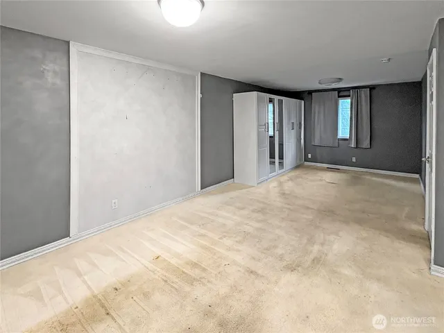 a view of an empty room with closet and a window