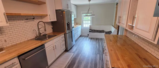 a kitchen with sink a refrigerator and wooden floor