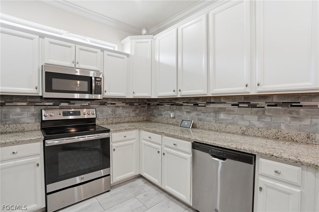 1936 Wellington Street Naples, FL 34120 - Photo 8 of 27 a kitchen with granite countertop white cabinets and stainless steel appliances