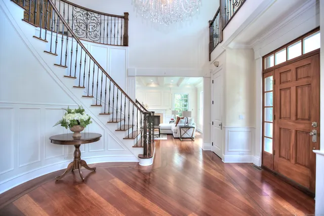 a view of a hallway with wooden floor table and chairs
