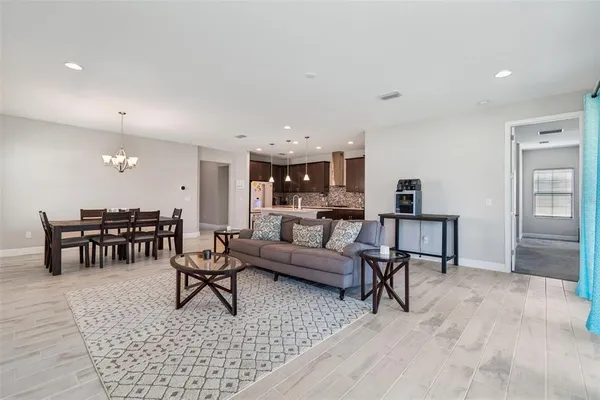 a kitchen with stainless steel appliances granite countertop a dining table chairs refrigerator and microwave