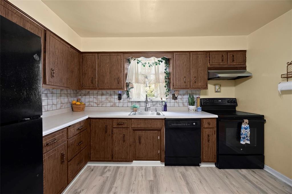 1421 Fleming Avenue McKees Rocks, PA 15136 - Photo 5 of 36 a kitchen with a sink dishwasher a stove and a refrigerator with wooden floor