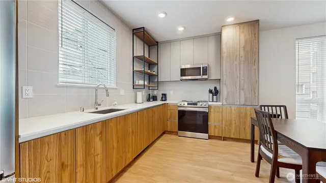 a kitchen with stainless steel appliances granite countertop a sink stove microwave and refrigerator