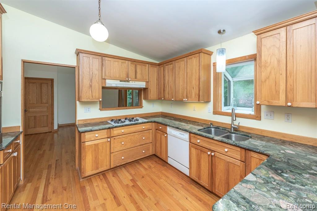 7870 Chamberlin Road Dexter, MI 48130 - Photo 5 of 52 Kitchen featuring wood-finish flooring, wood cabinetry, stone countertops, dual basin sink, and a built-in cooktop