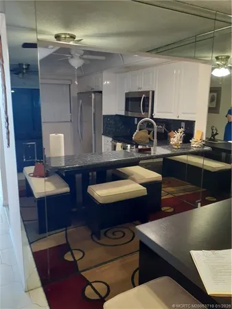 a kitchen with stainless steel appliances granite countertop a sink a stove white cabinets and chairs