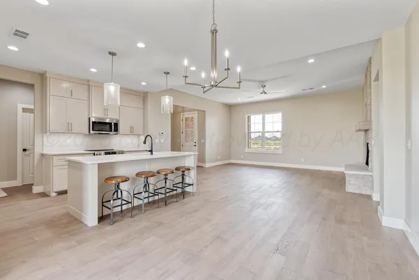 a kitchen with stainless steel appliances granite countertop a sink dishwasher stove and white cabinets with wooden floor