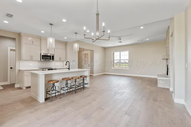 a kitchen with stainless steel appliances granite countertop a sink dishwasher stove and white cabinets with wooden floor