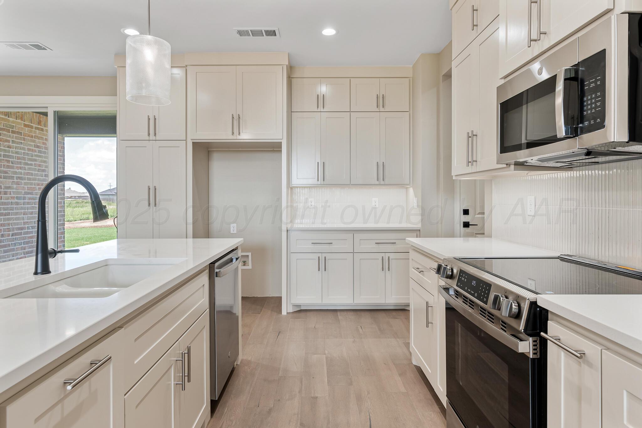 19100 Buck Springs Road Amarillo, TX 79119 - Photo 13 of 29 a kitchen with stainless steel appliances granite countertop a sink dishwasher stove and white cabinets with wooden floor