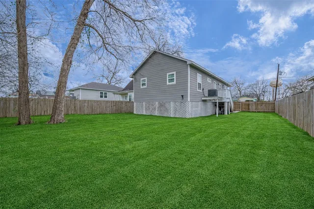 a view of a house with a yard and a large tree