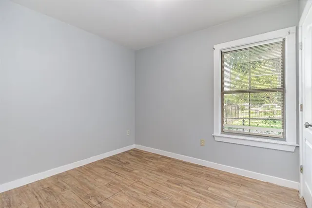 an empty room with wooden floor and a window