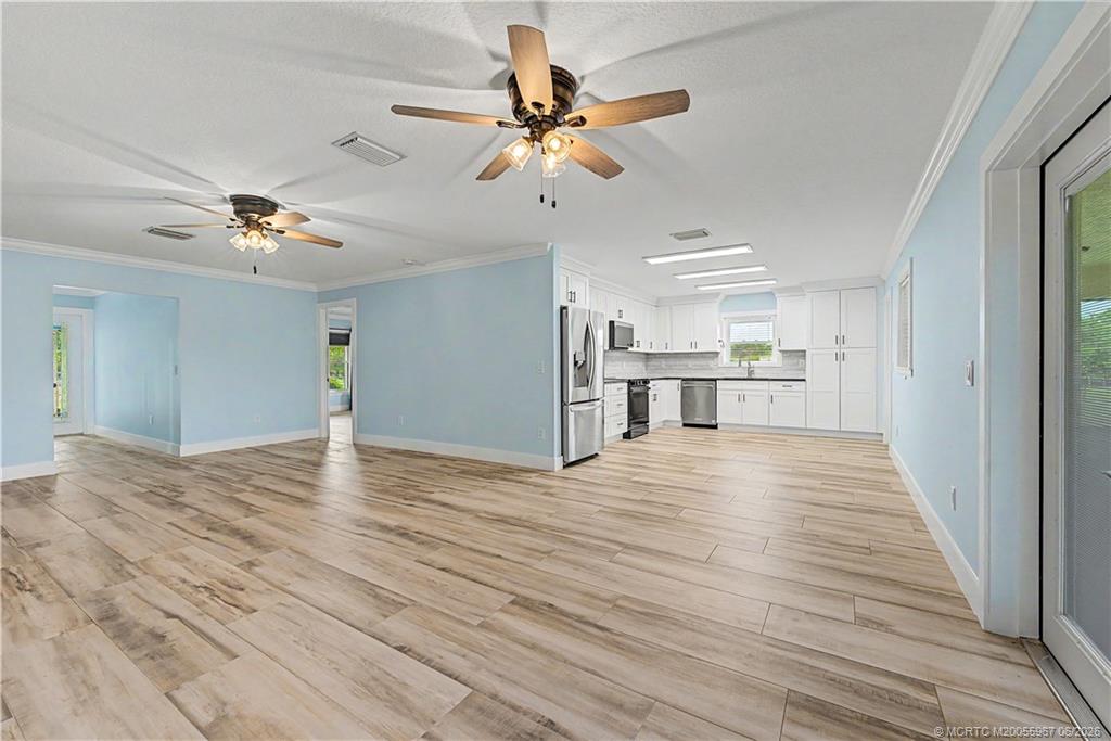 8200 Southwest Springhaven Avenue Indiantown, FL 34956 - Photo 4 of 35 a view of an empty room and kitchen space with wooden floor