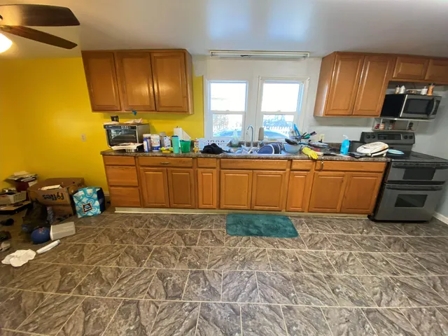 a kitchen with granite countertop a stove a sink and a wooden cabinets