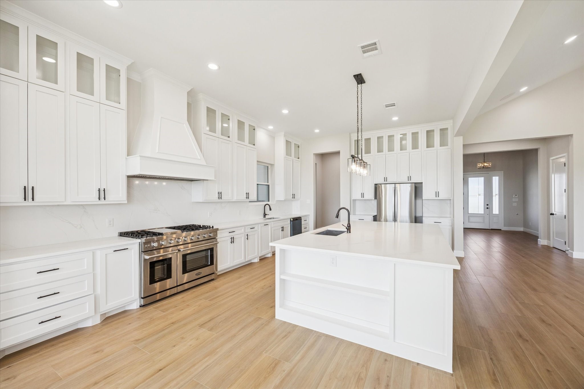 27645 Spring Hill Road Hempstead, TX 77445 - Photo 8 of 32 a large white kitchen with kitchen island a stove a sink dishwasher and white cabinets with wooden floor