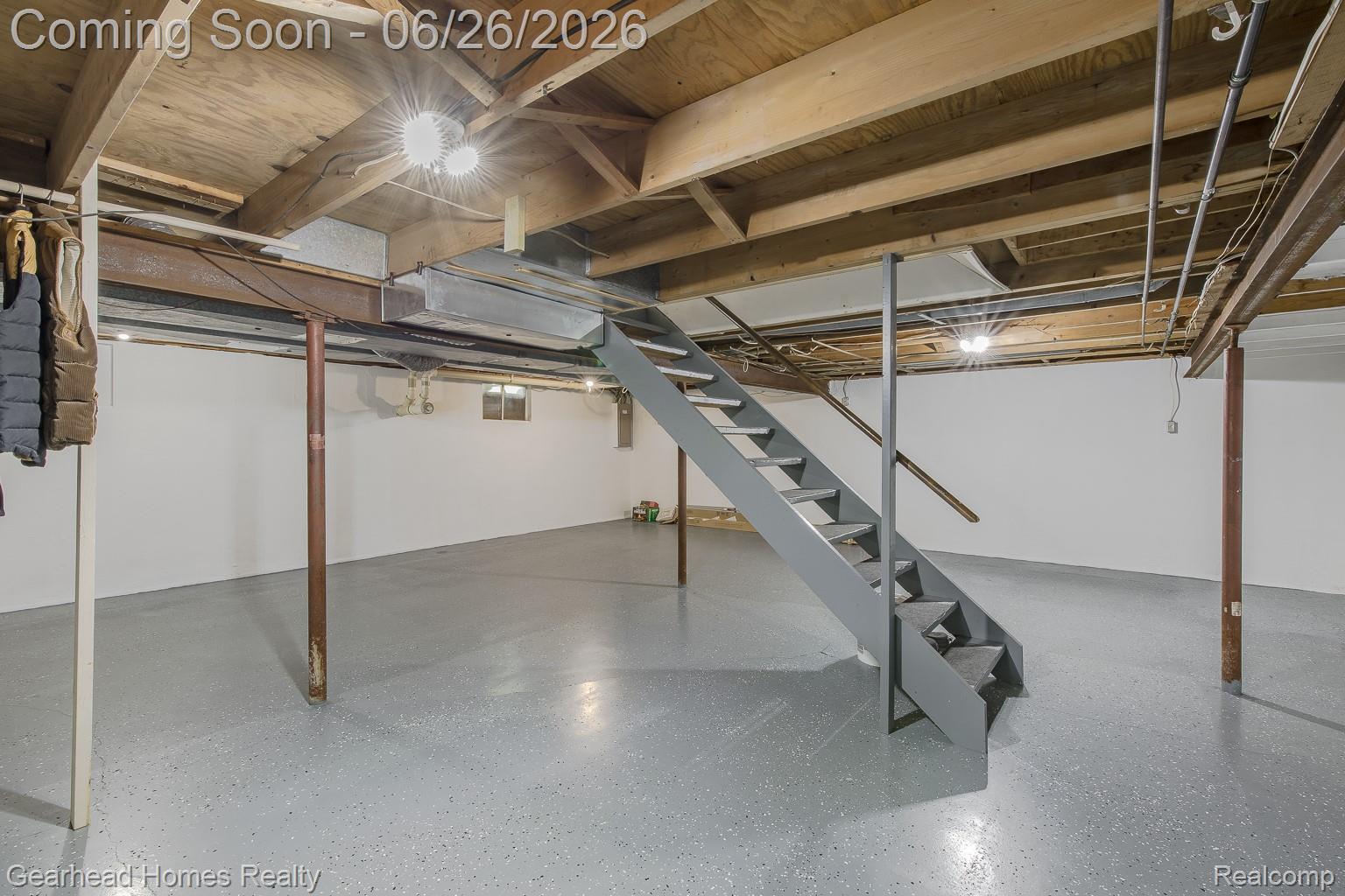 12364 Morrish Road Clio, MI 48420 - Photo 45 of 81 Finished basement space featuring a gray painted concrete floor, exposed wood ceiling beams, painted white walls, and a gray painted staircase with a metal handrail