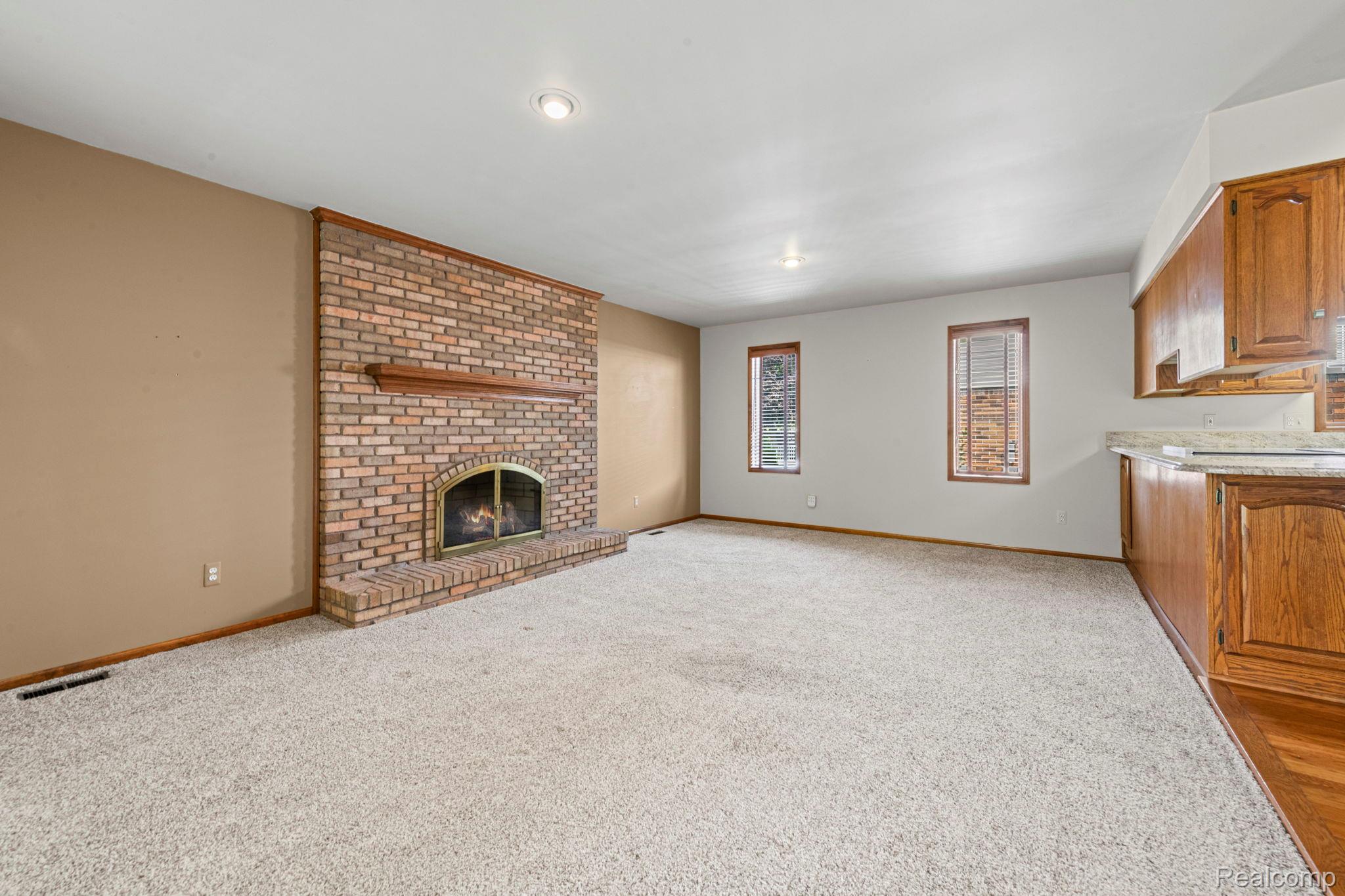 21580 Georgetown Road Trenton, MI 48183 - Photo 13 of 36 Spacious living area featuring a brick fireplace with a wood mantel, light-toned carpeting, recessed lighting, and two windows