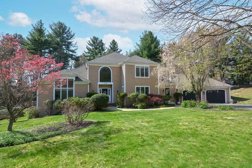 a front view of a house with garden and trees