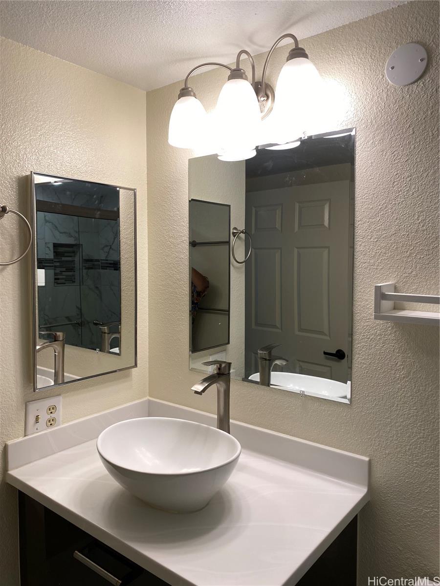 3075 Ala Poha Place, Unit 2111 Honolulu, HI 96818 - Photo 7 of 9 a bathroom with a sink a mirror and a shower