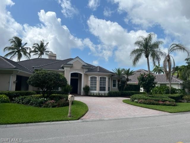 938 Spanish Moss Trail Naples, FL 34108 - Photo 3 of 11 a front view of a house with a garden and trees