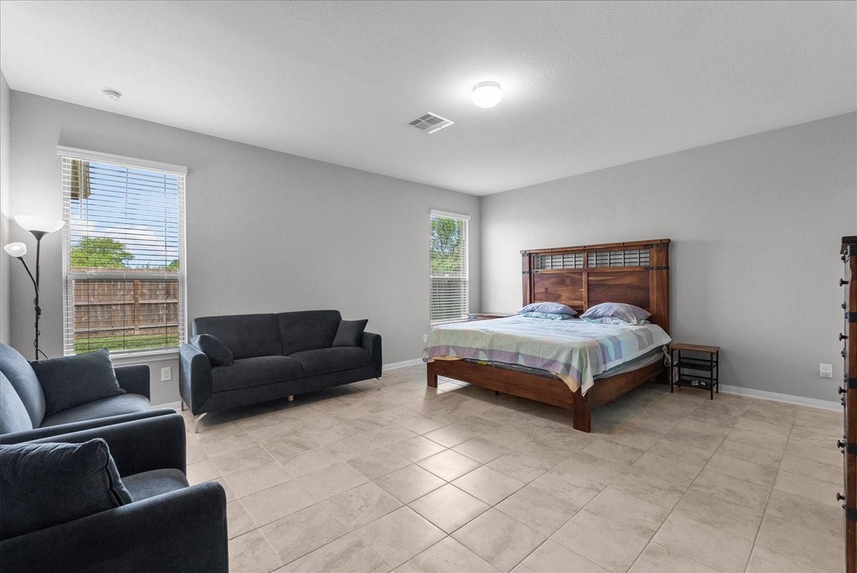 2320 Rosemary Street Rosenberg, TX 77469 - Photo 20 of 40 This spacious primary bedroom features a large window with natural light, tiled flooring, and neutral walls. It includes a cozy sitting area.
