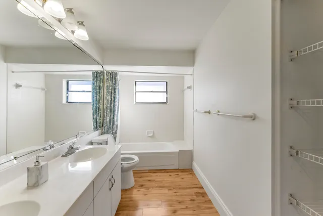 a bathroom with a granite countertop double vanity sink a mirror and a shower