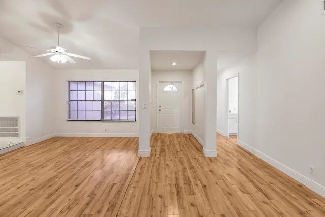 an empty room with wooden floor and windows