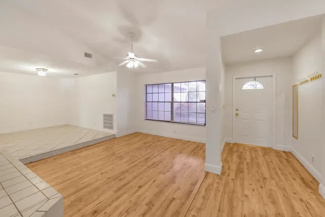 a view of empty room with wooden floor and fan