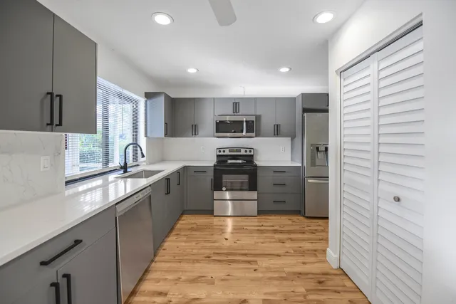 a large kitchen with stainless steel appliances kitchen island granite countertop a refrigerator and a sink