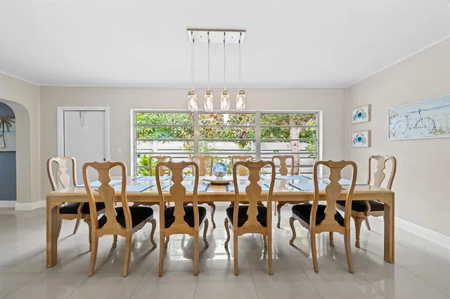 a view of a dining room with furniture a chandelier and large windows