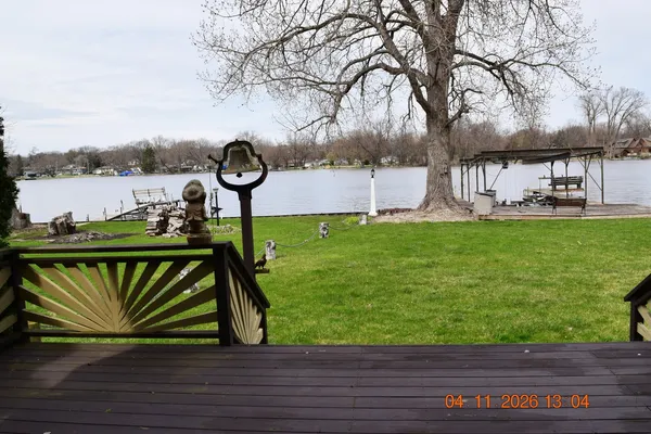 a view of a lake with a bench and large trees