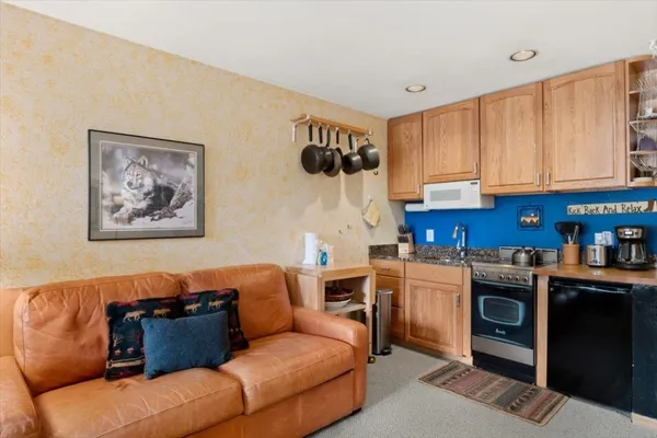 a living room with furniture a flat screen tv and kitchen view