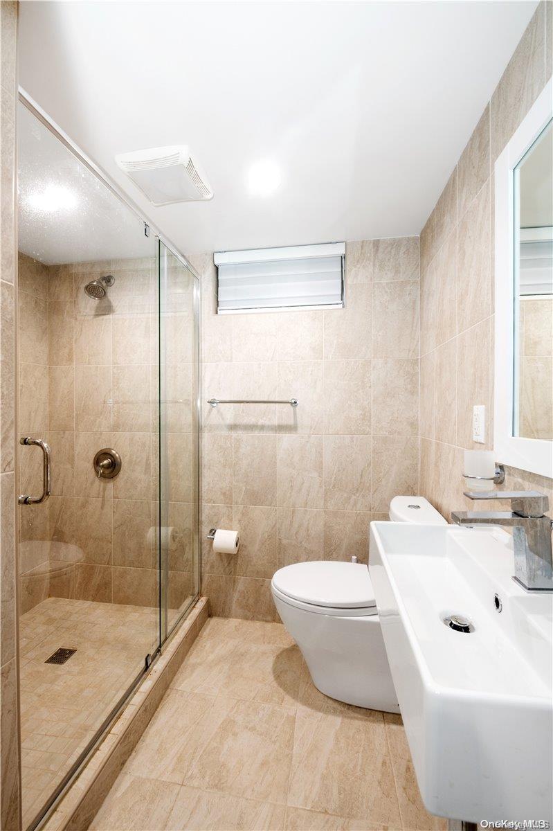 29-33 212th Street, Unit 1F Queens, NY 11360 - Photo 12 of 14 Full bathroom featuring a shower stall and tile walls