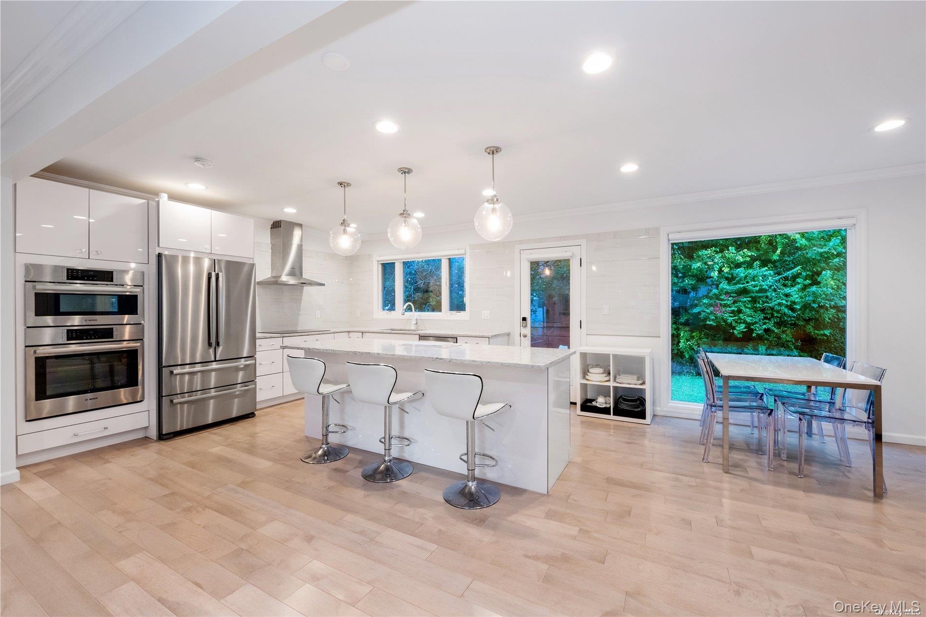 29-33 212th Street, Unit 1F Queens, NY 11360 - Photo 3 of 14 Kitchen with stainless steel appliances, pendant lighting, white cabinetry, a kitchen island, and a breakfast bar area