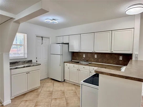 a kitchen with a sink a refrigerator and cabinets