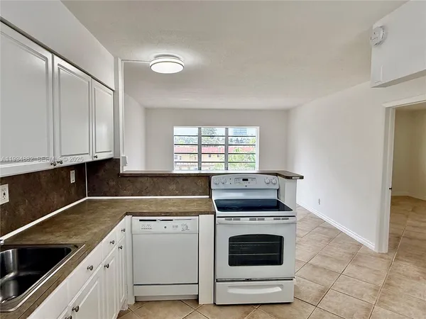 a kitchen with granite countertop white cabinets and white appliances