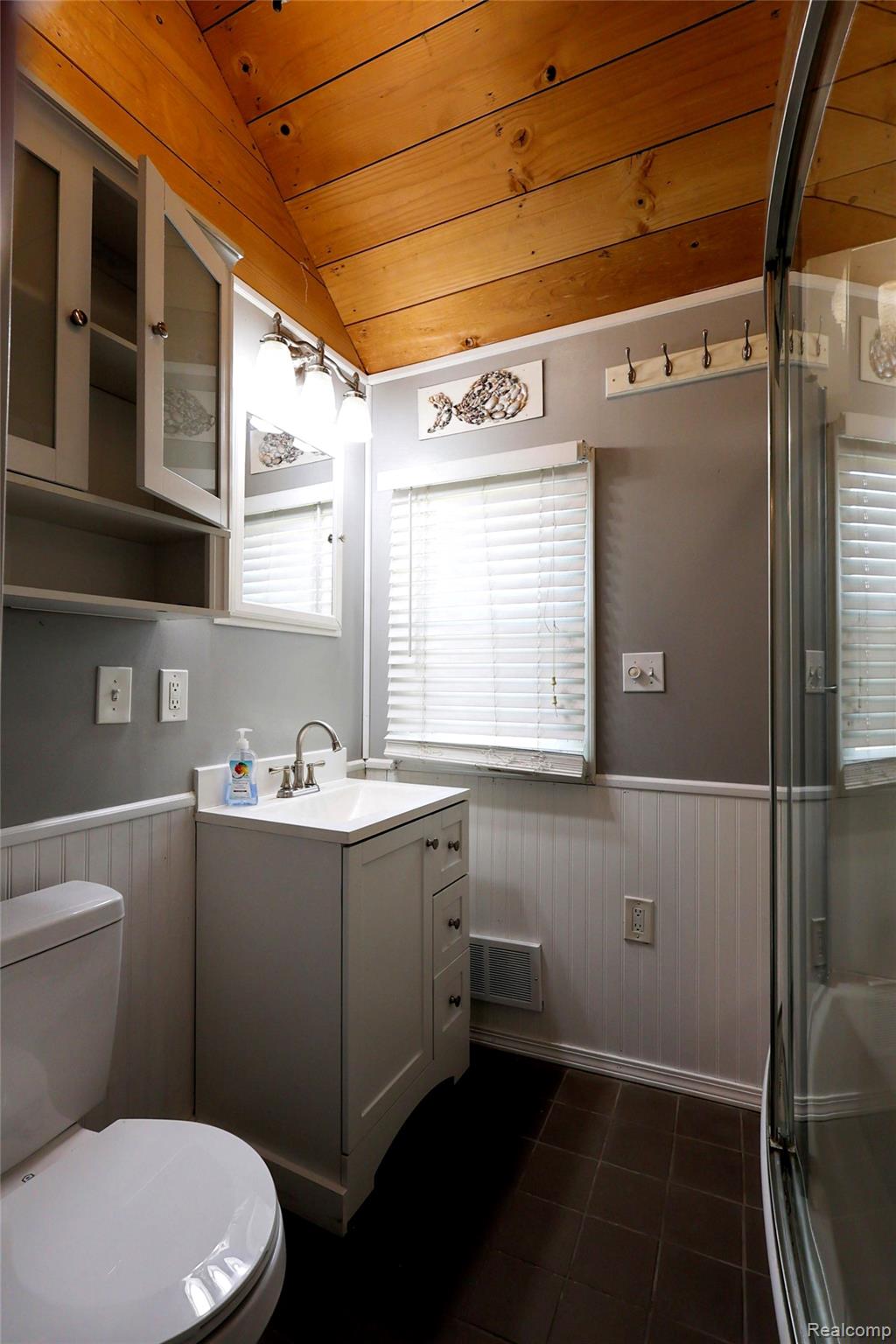 15676 Frazho Road Roseville, MI 48066 - Photo 8 of 20 Bathroom featuring a wood-paneled vaulted ceiling, white beadboard wainscoting, and dark tile flooring